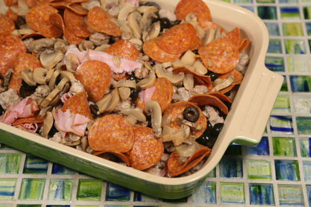 Fill a casserole dish with the sausage, pepperoni, ham, mushrooms, and black olives.
