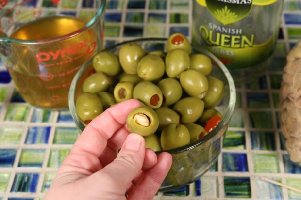If the olives are stuffed with pimento, push it out with a toothpick. Stuff each olive with a Marcona almond.