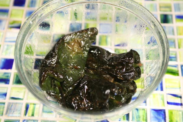 Transfer the chiles to a bowl and cover with cling wrap to steam for 5 minutes, which loosens the skin.